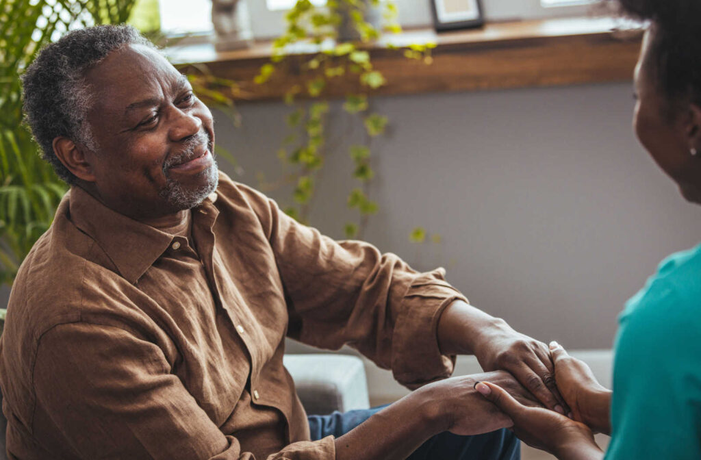 Senior male having his hands held by a loved one.