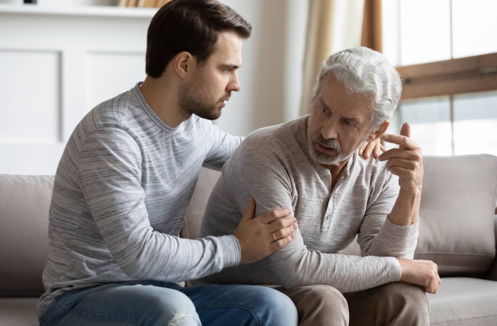 A stressed adult child trying to comfort their frustrated older parent.